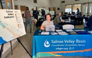 A woman sitting at a SVBGSA table next to a map