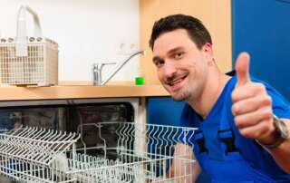 A man giving a thumbs up in front of an open dishwasher